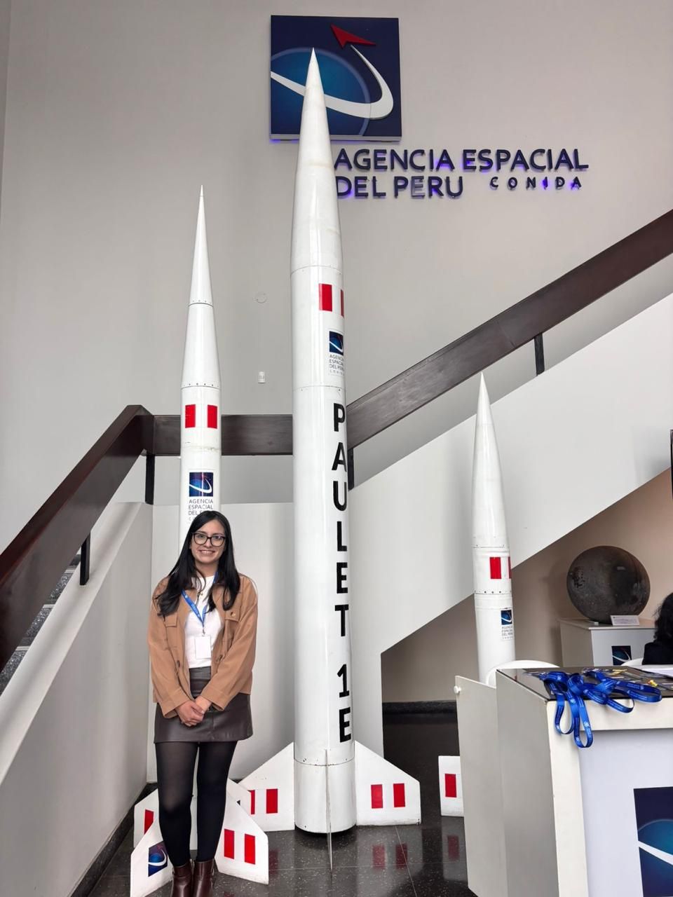 Aurora Britania Diaz Fernandez standing beside the Paulet sounding rockets at CONIDA, the Peruvian Space Agency.